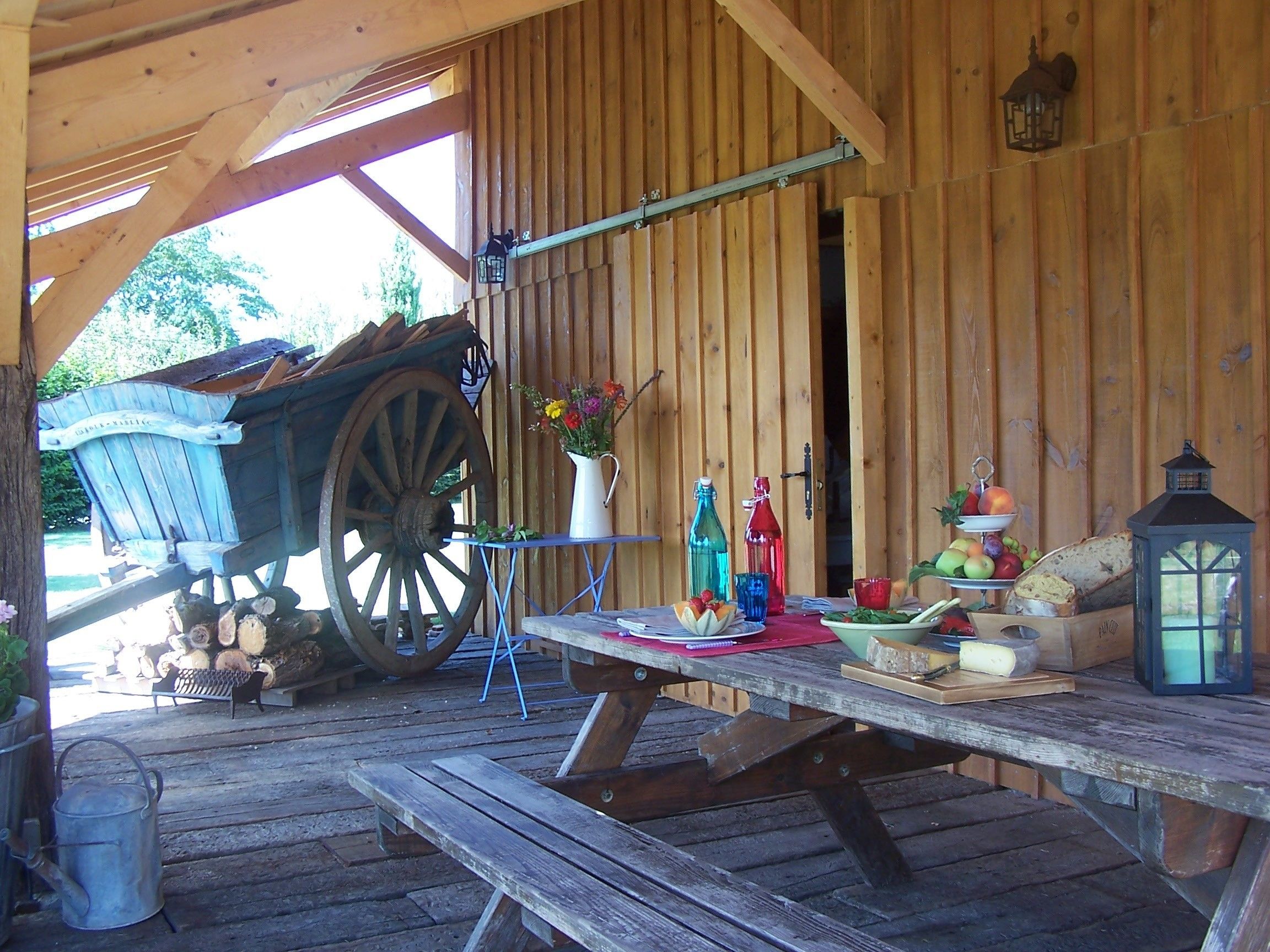 Un rústico granero de madera con una mesa de madera dispuesta para comer, mostrando una variedad de frutas, verduras y pan.