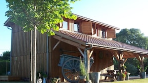 Un bâtiment en bois de style grange, doté d’un toit en tuiles, de grandes fenêtres et d’un porche abrité.