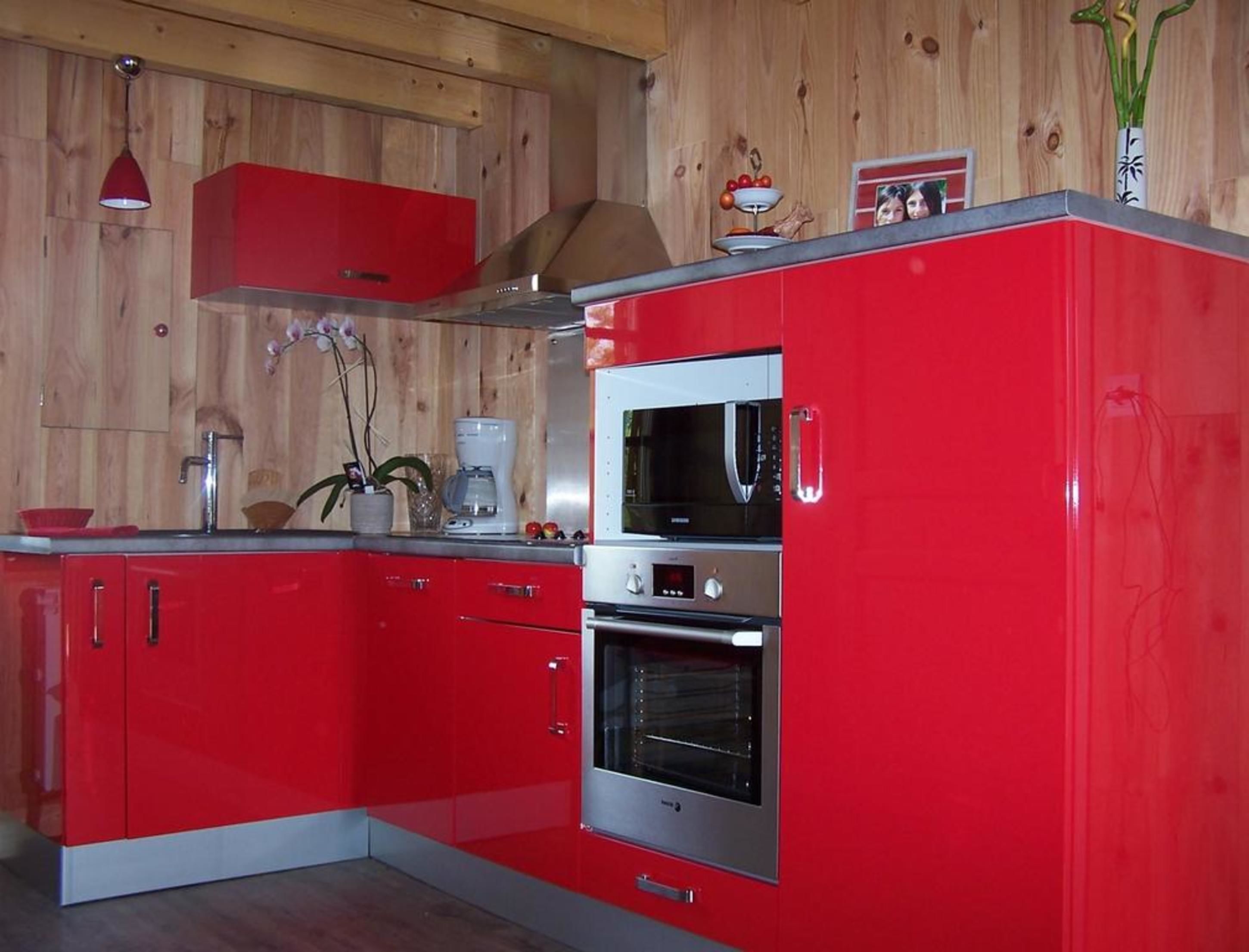 A compact kitchen with red cabinetry, a microwave, an oven, and a coffee maker.