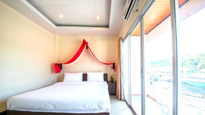 Una habitación de hotel moderna con una cama grande, una mesita de noche con un florero y vistas a la ciudad a través de amplias ventanas.