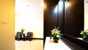 Un área de recepción con mostrador, dos sillas y un jarrón de flores.