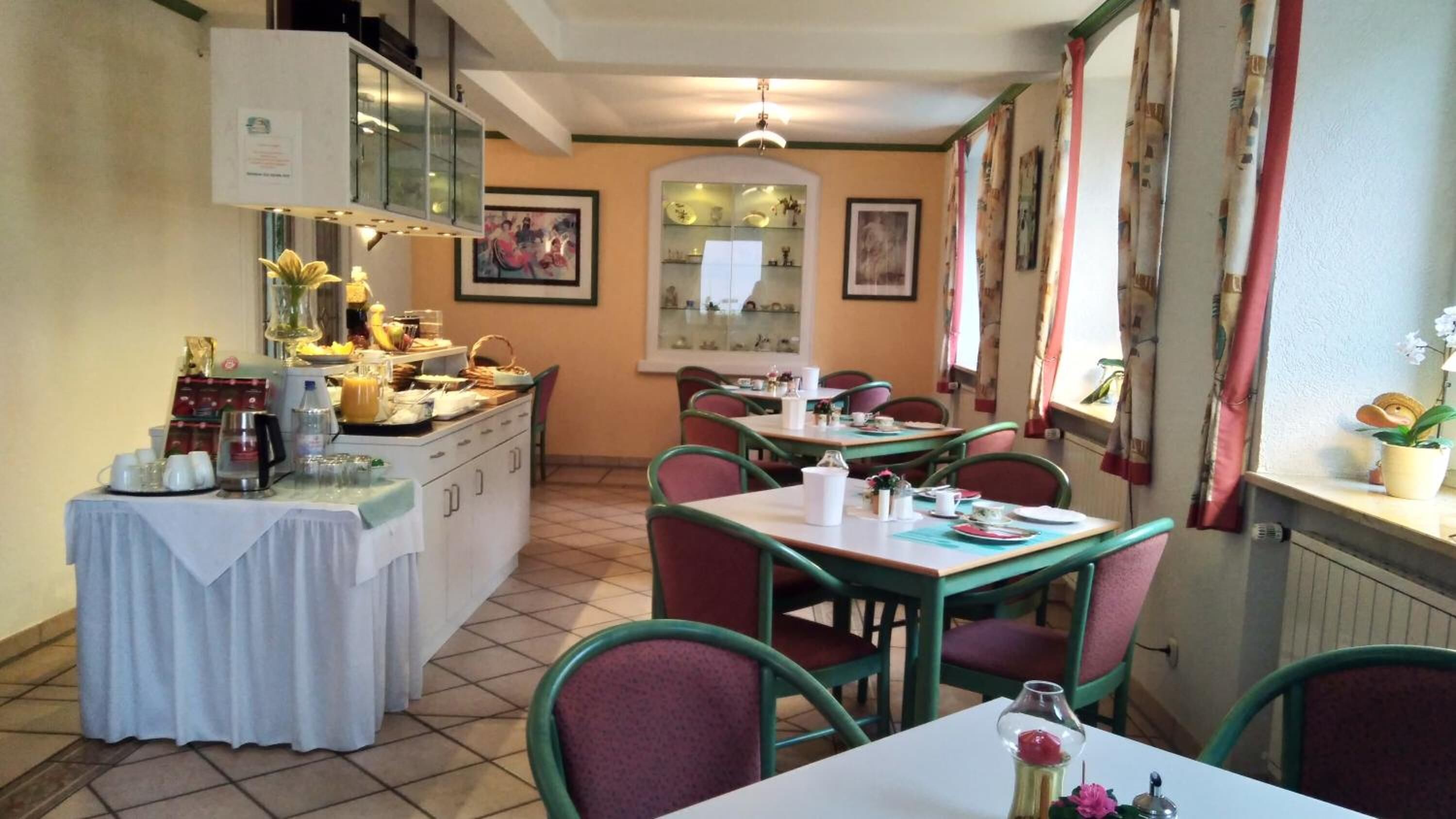 A dining area with tables and chairs, a buffet counter with food and drinks, and a mirror on the wall.