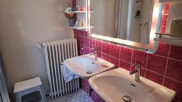 Et badeværelse med to håndvaske, et spejl, en radiator og en lille skammel.