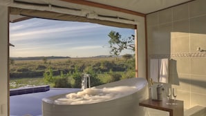 A modern bathroom with a large bathtub, a view of a natural landscape, and a wooden vanity. - Ngerende in the Wild Lakeview (Maasai Mara)