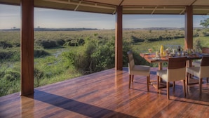 A dining area with a table set for two, overlooking a natural landscape. - Ngerende in the Wild Lakeview (Maasai Mara)