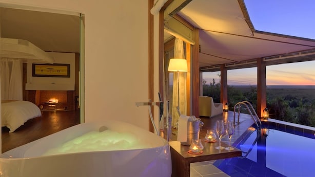 A luxurious bedroom with a large bathtub, a dining area with a view, and a poolside setting with a sunset view. - Ngerende in the Wild Lakeview (Maasai Mara)