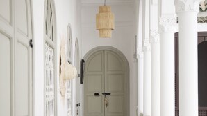 Un couloir avec une porte blanche, un banc et un luminaire suspendu.