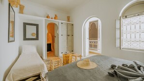 Une chambre à coucher avec un lit, une petite table et une porte donnant sur une autre pièce.