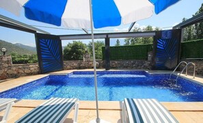 Una piscina al aire libre, sombrillas, sillones reclinables de piscina
