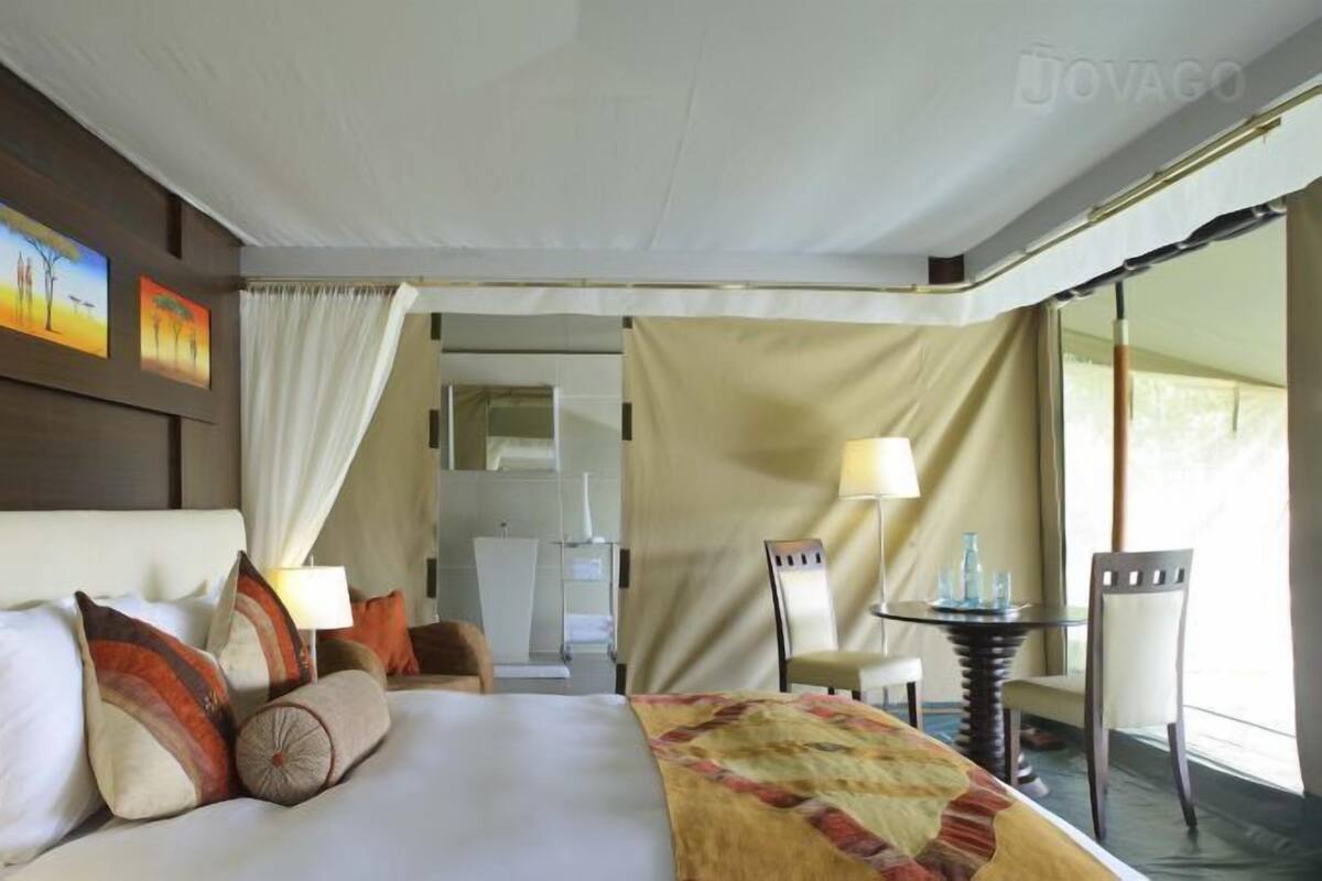 Quarto de hotel com cama, escrivaninha, cadeira e vista para o exterior.