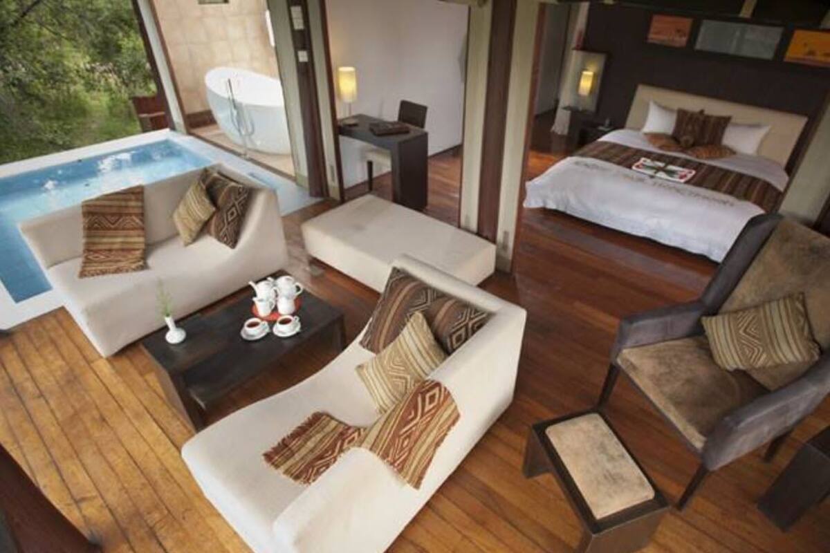 Un suite d'hotel modern amb piscina privada, zona de dinar i dormitori.