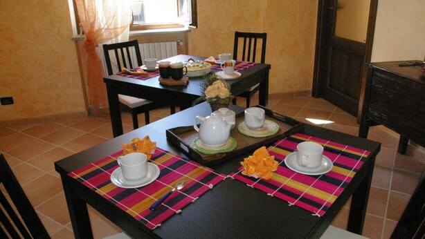 A dining area with a table set for two, featuring a teapot, cups, and a floral centerpiece. - Bed & Breakfast Cascina Bellezza (Poirino)
