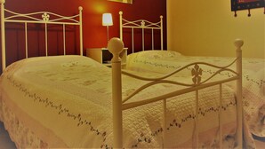 A double bed with a white frame and floral bedding, a bedside table with a lamp, and a wall-mounted painting of tulips. - Bed & Breakfast Cascina Bellezza (Poirino)