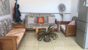 A living room with a sofa, a coffee table, a refrigerator, and a fan. - Guo House (Changping)