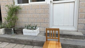 A wooden chair outside a building with a tiled facade and a door. - Guo House (Changping)