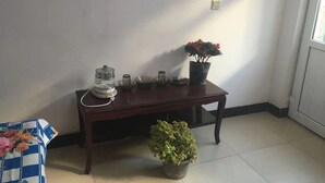 A wooden table with a coffee maker, a potted plant, and a small table lamp. - Guo House (Changping)