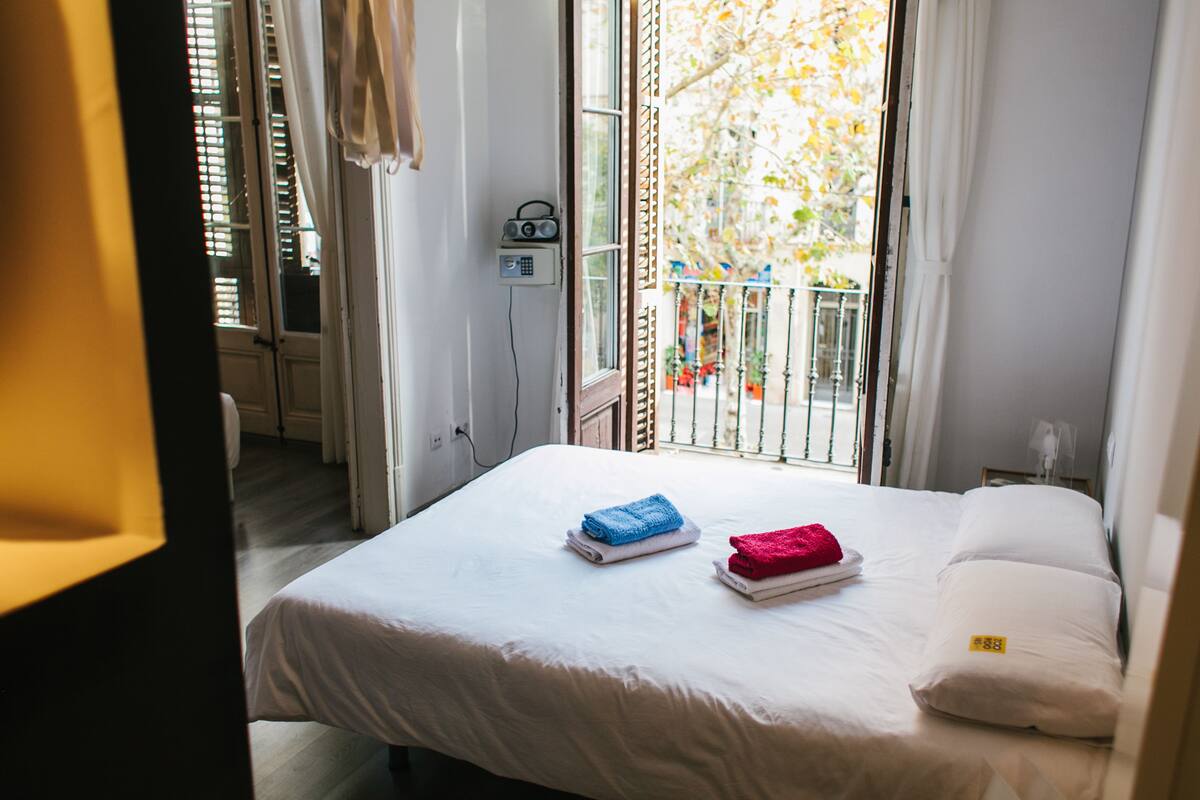 Een hotelkamer met een bed, een raam met uitzicht en een radio aan de muur.