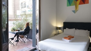 A hotel room with a bed, a table with chairs, a window, and a wall art piece. - ZOOROOMS Boutique GuestHouse (Barcelona)