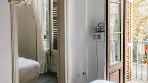 A hotel room with a bed, a window with a view, a door leading to another room, and a radio on the wall. - ZOOROOMS Boutique GuestHouse (Barcelona)