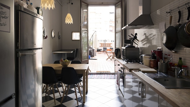 A modern kitchen with a refrigerator, dining table, chairs, and a view of the outside. - ZOOROOMS Boutique GuestHouse (Barcelona)