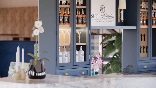 A hotel reception area with a blue cabinet displaying liquor bottles and glasses, a sign reading "SLOTTS GÅRDEN HOTEL OCH RESTAURANG," and a potted plant with white flowers. - Hotel Slottsgården (Vadstena)