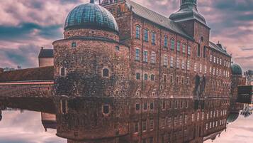 A historic building with a prominent dome and a tall tower, reflected in a body of water.
