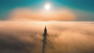 Gebäudesilhouette vor einem Sonnenaufgang, umgeben von Nebel.