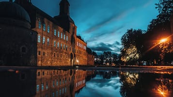 Un edificio histórico con una gran cúpula y una torre alta, reflejado en aguas tranquilas.
