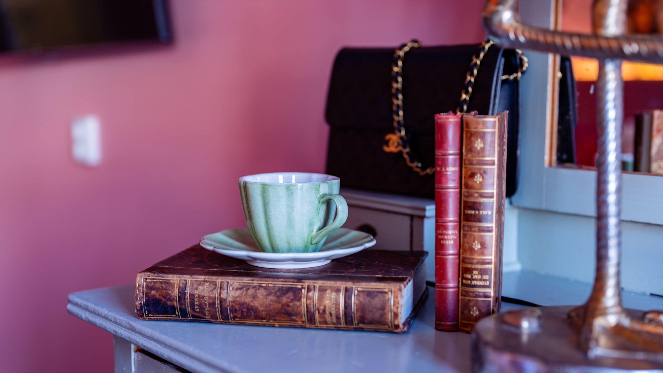 A table with a green cup, a saucer, and two books.