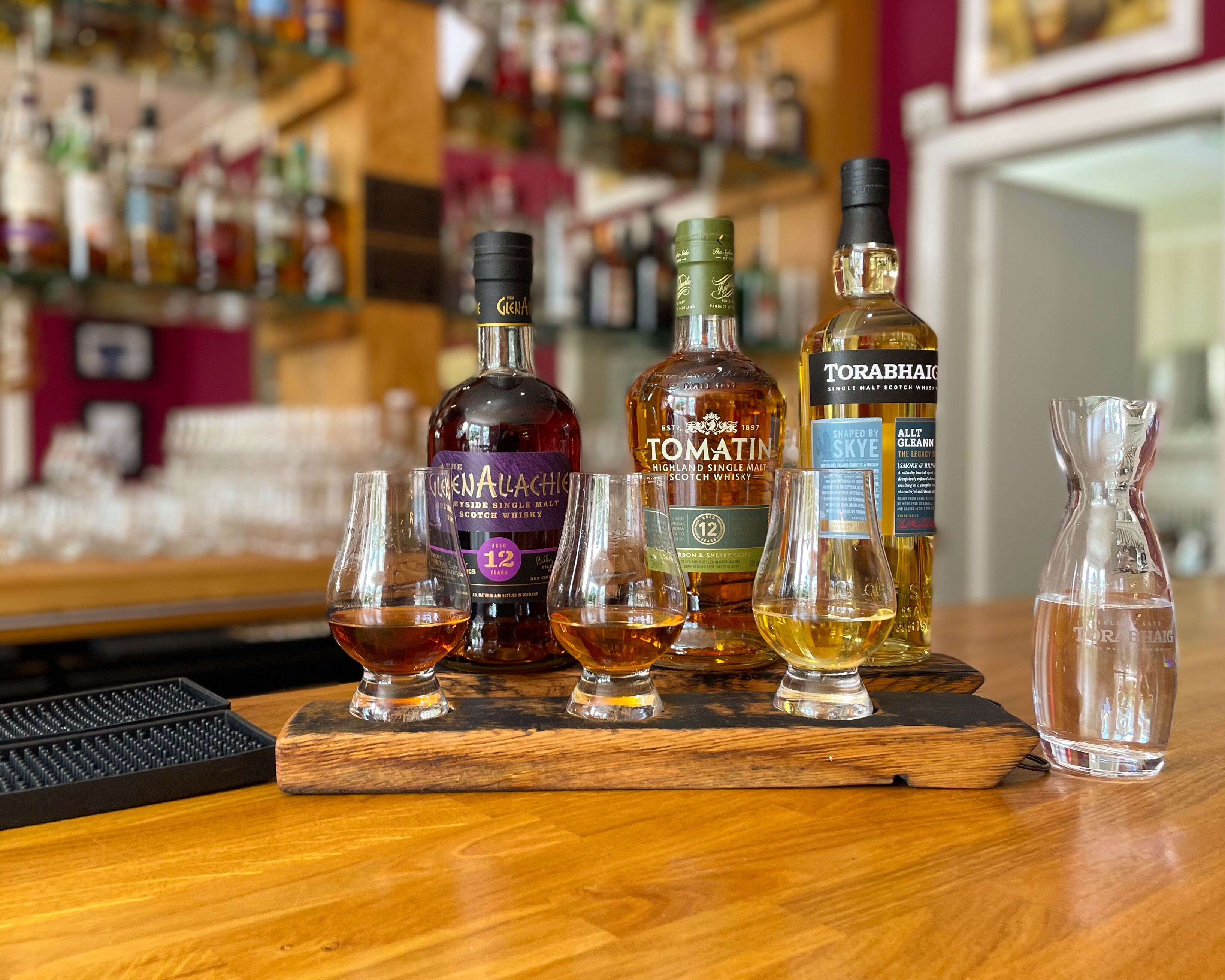 Un bar avec différentes bouteilles de whisky et des verres.
