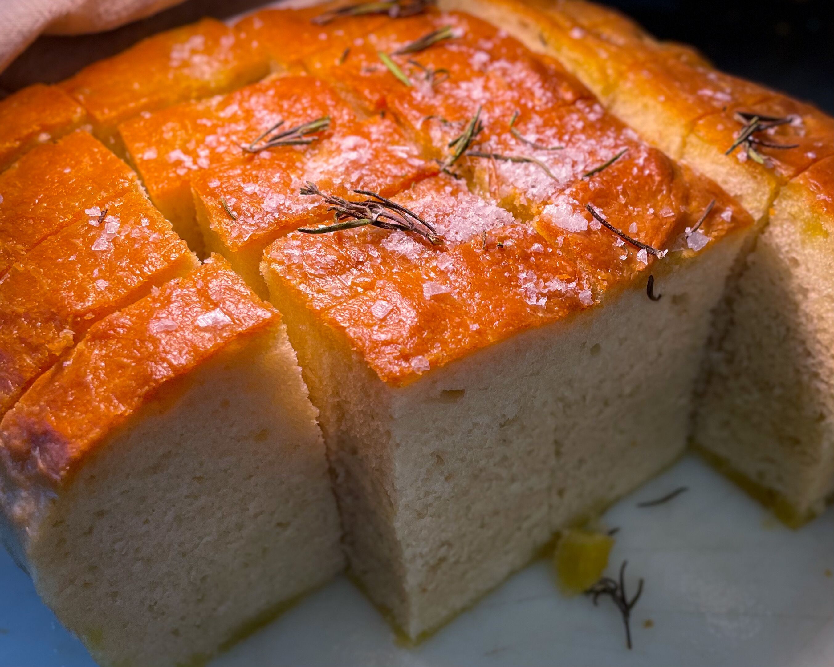 Ein Detailaufnahme eines Kuchens mit goldbrauner Kruste, bestreut mit Kräutern und Salz.
