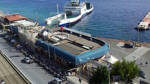A ferry docked at a port with a clear view of the sea and distant land. - Nettuno (Messina)