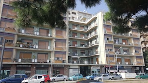 A multi-story residential building with balconies, some with potted plants. - Nettuno (Messina)