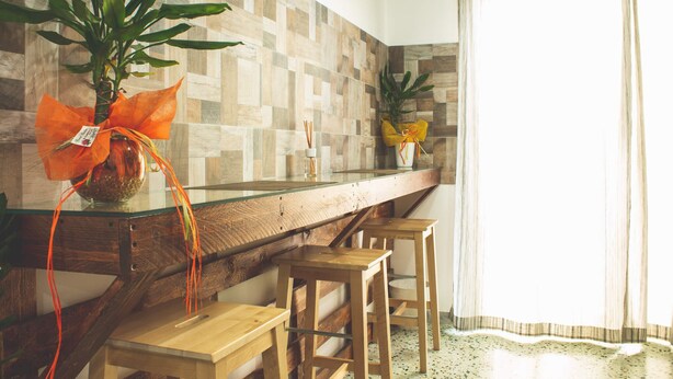 A kitchen with a wooden countertop, two stools, and a potted plant with an orange ribbon. - Nettuno (Messina)