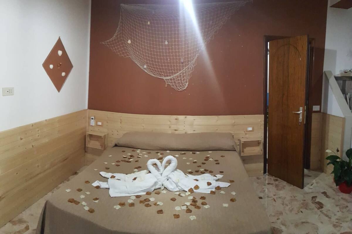 A hotel room with a bed, a wooden headboard, a wall-mounted net, and a door.