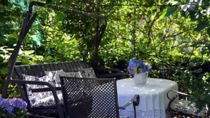 A garden patio with a round table, a chair, and a flower vase. - Hotel Ebnet Garni (Lindau)