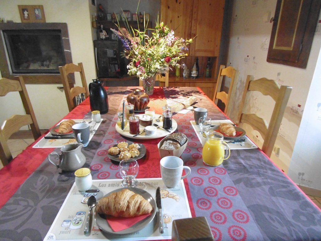 A breakfast table set with croissants, bread, pastries, and beverages.