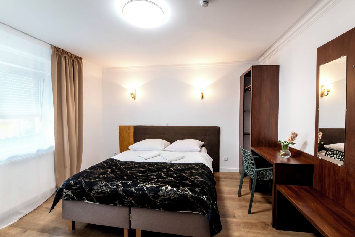 A modern bedroom with a bed, bedside table, chair, and wardrobe.