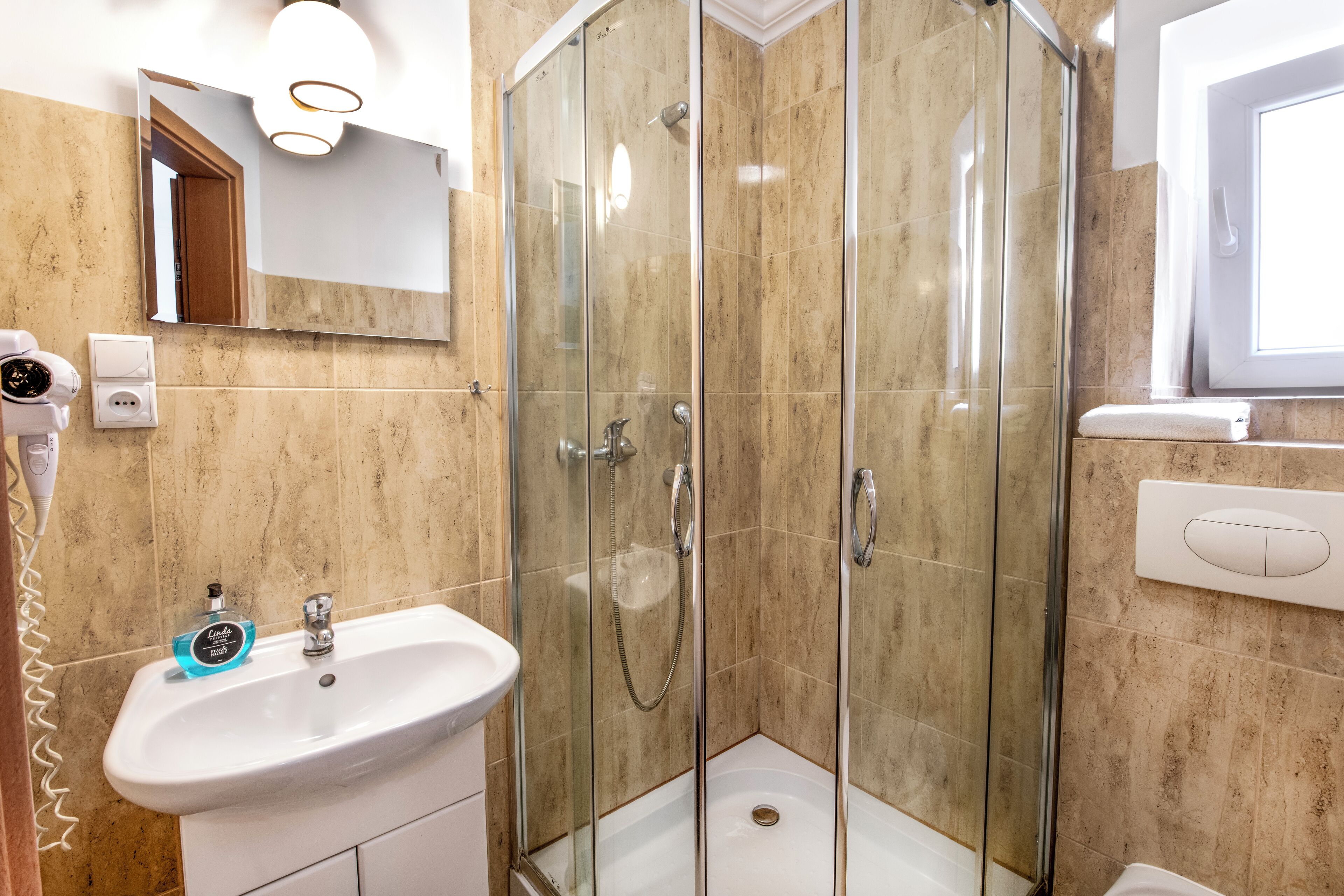 Un baño con ducha envuelta en vidrio, un lavabo y un espejo.
