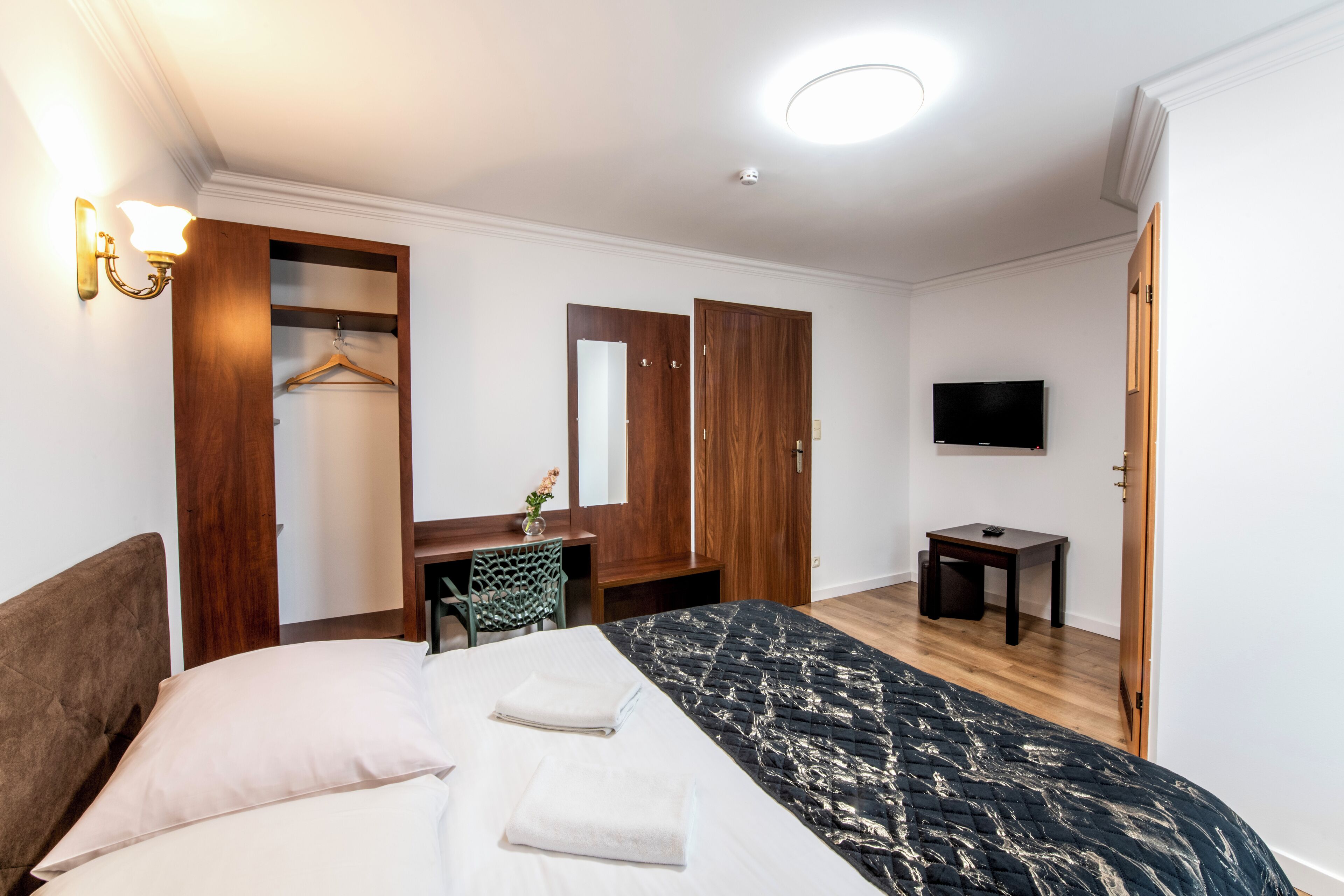 Une chambre d’hôtel équipée d’un lit, d’un bureau, d’une chaise, d’une télévision et d’une armoire.