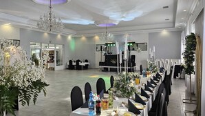 A banquet hall with long tables, chandeliers, and floral decorations. - Noclegi Europa (Boleslawiec)