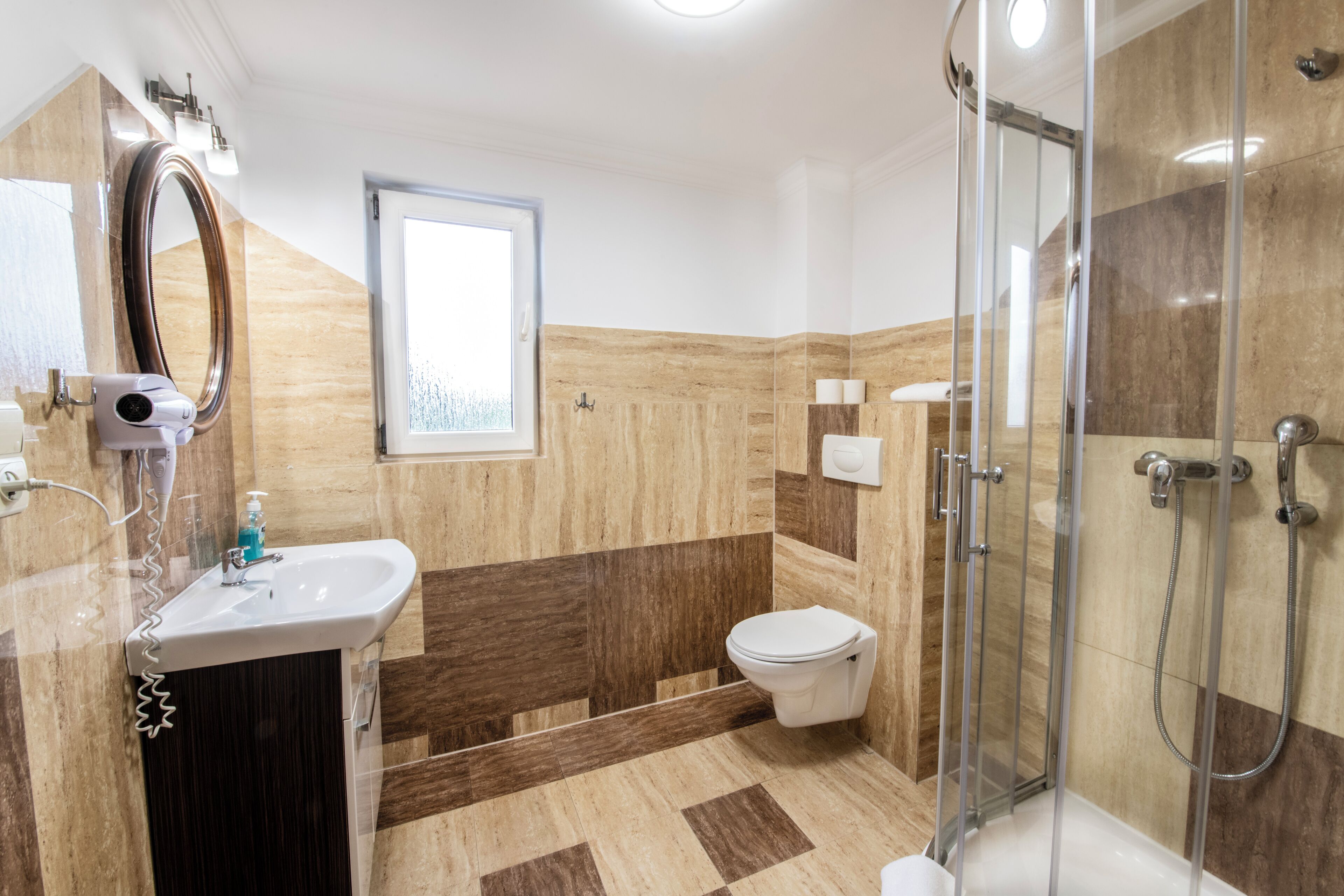 A modern bathroom with a glass-enclosed shower, a white sink, and a toilet.