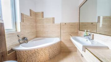 Een moderne badkamer met een vrijstaand bad, een grote spiegel en een wastafel.