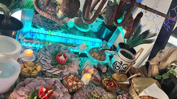 A table with various food items, including sliced meats, cheeses, and vegetables, arranged on a tablecloth. - Noclegi Europa (Boleslawiec)