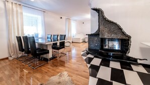 A modern living room with a fireplace, a dining area with chairs and a table, and a checkered floor. - Noclegi Europa (Boleslawiec)