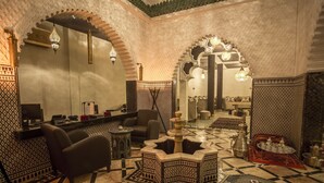 A traditional Moroccan interior with a checkered floor, ornate arches, and a seating area with a coffee table. - Palais Dar Si Aissa ALL-SUITES (Marrakech)