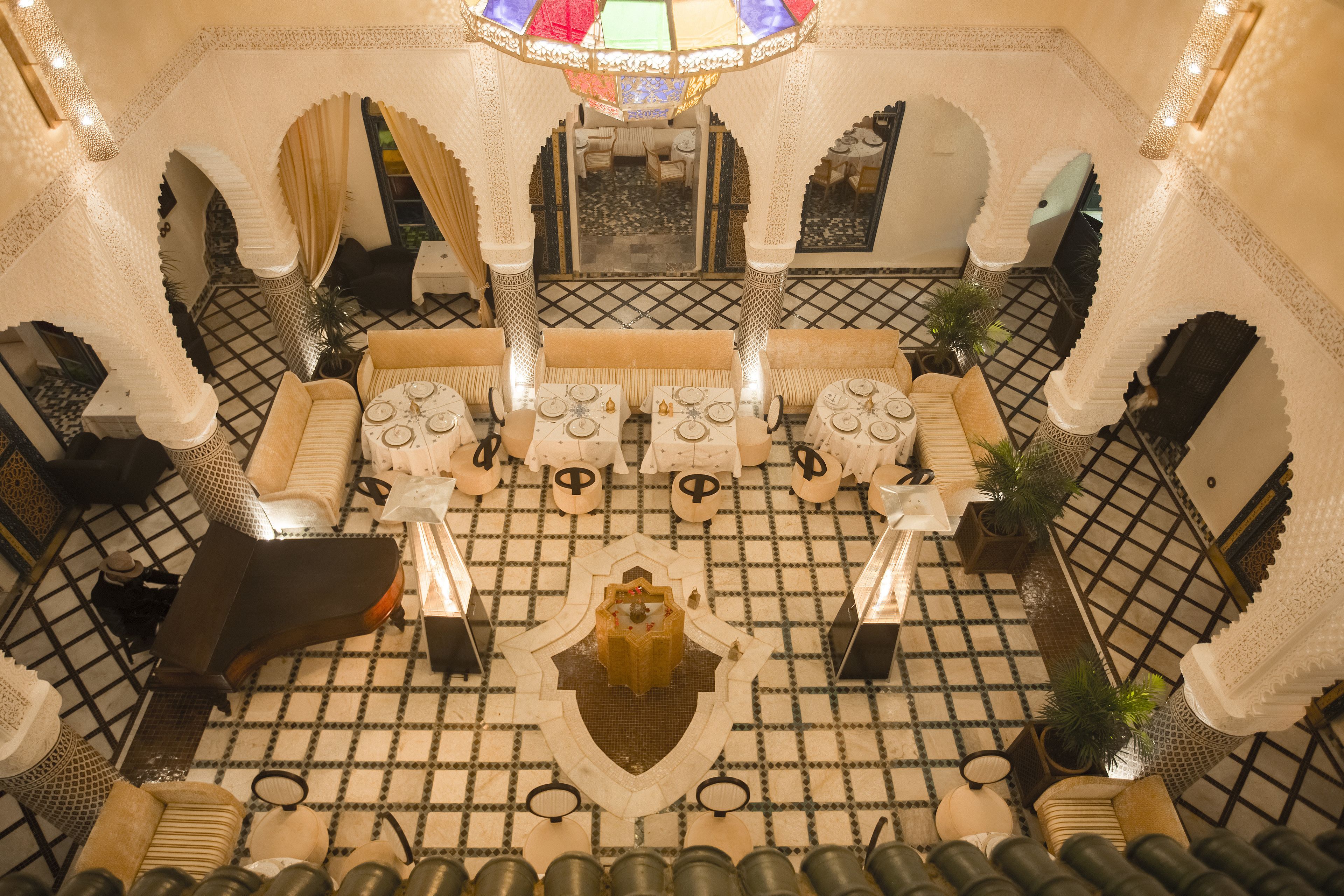 An ornate interior with a central fountain, seating area, and patterned floor.