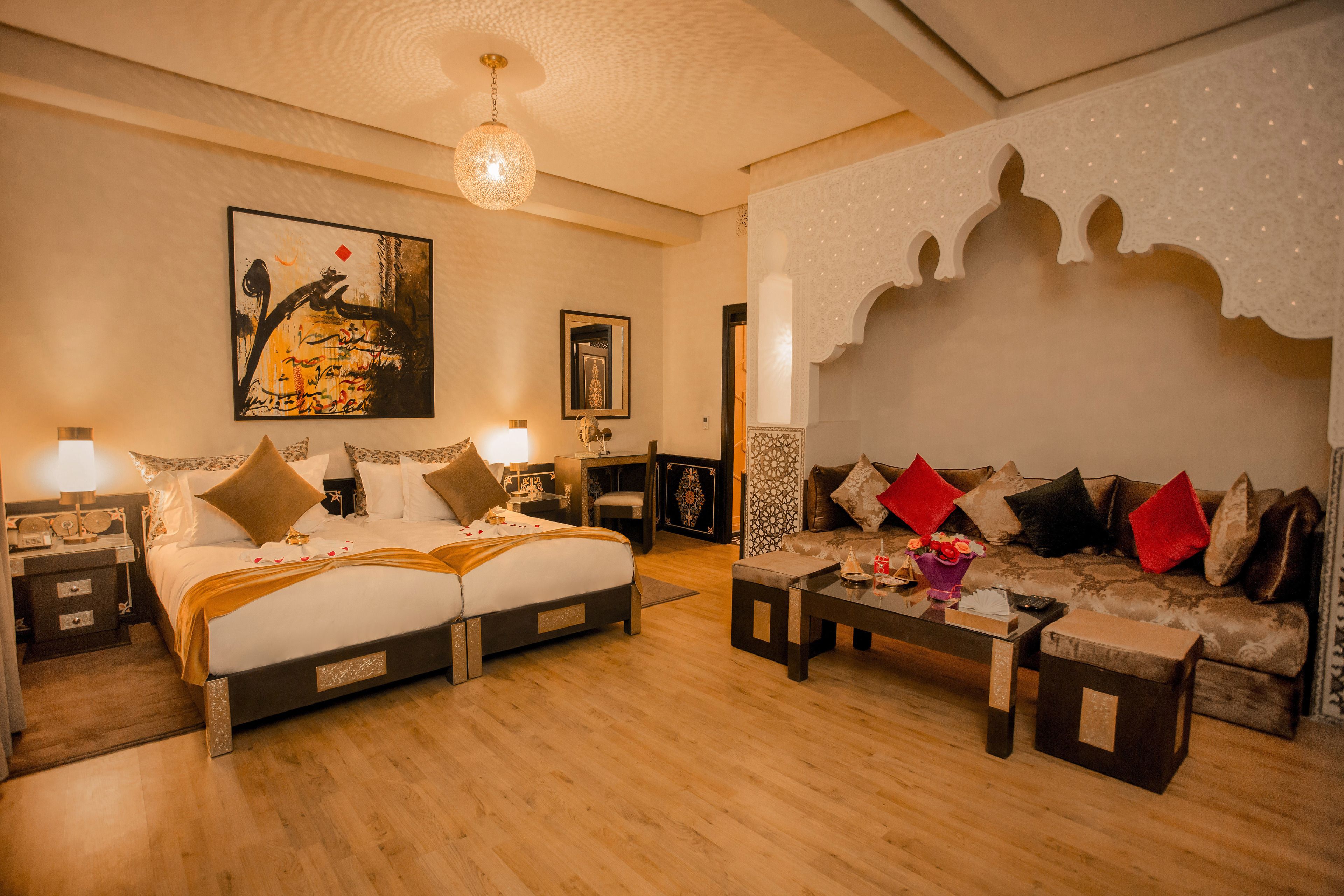 A hotel room with a bed, a sofa, a coffee table, and a decorative wall.