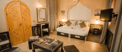 Una habitación de hotel con una cama grande, una puerta de madera, una pequeña mesa, una silla y un televisor.
