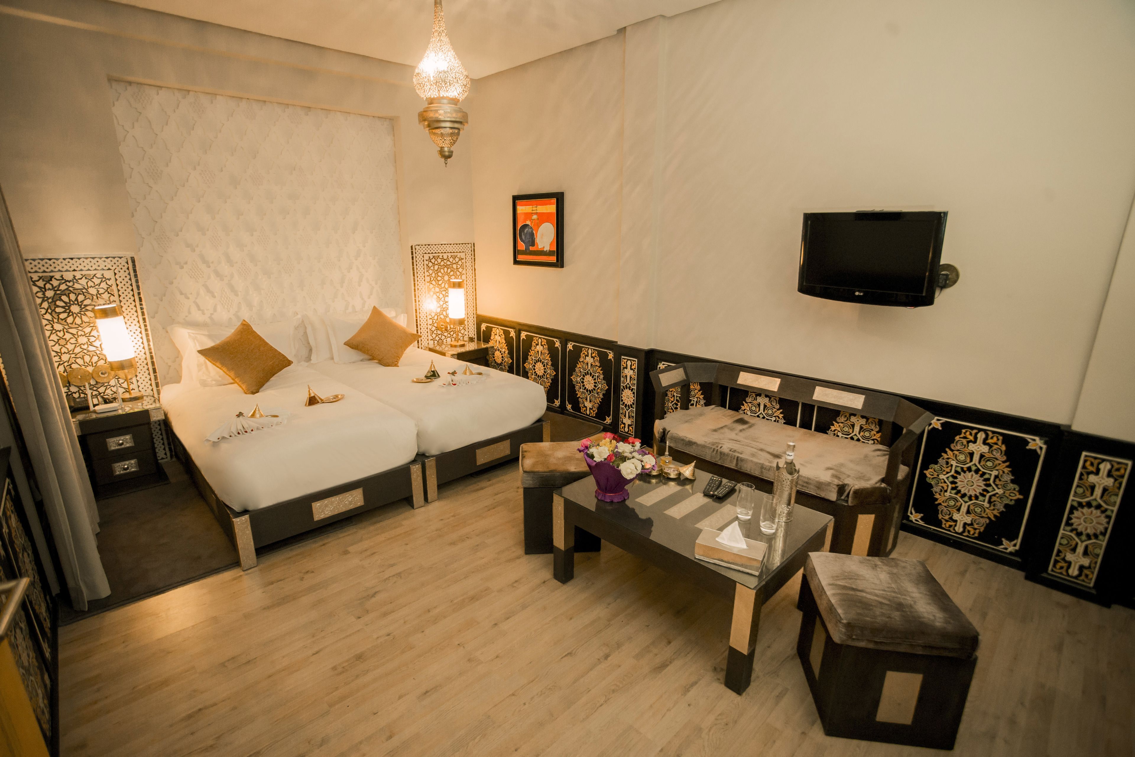 Una camera d'albergo con un letto, un divano, una TV e un tavolo con un vaso di fiori.